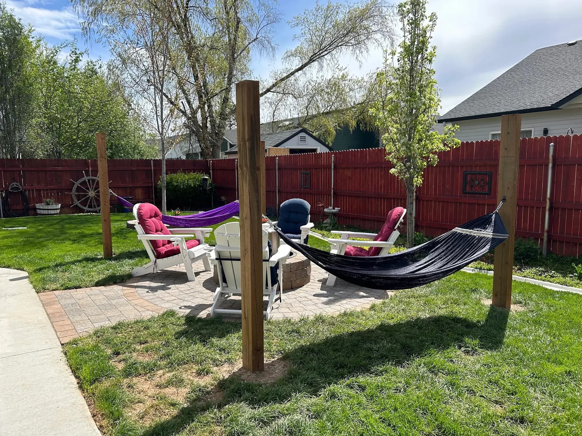 circular paver patio with stone fire pit hammocks and backyard fencing