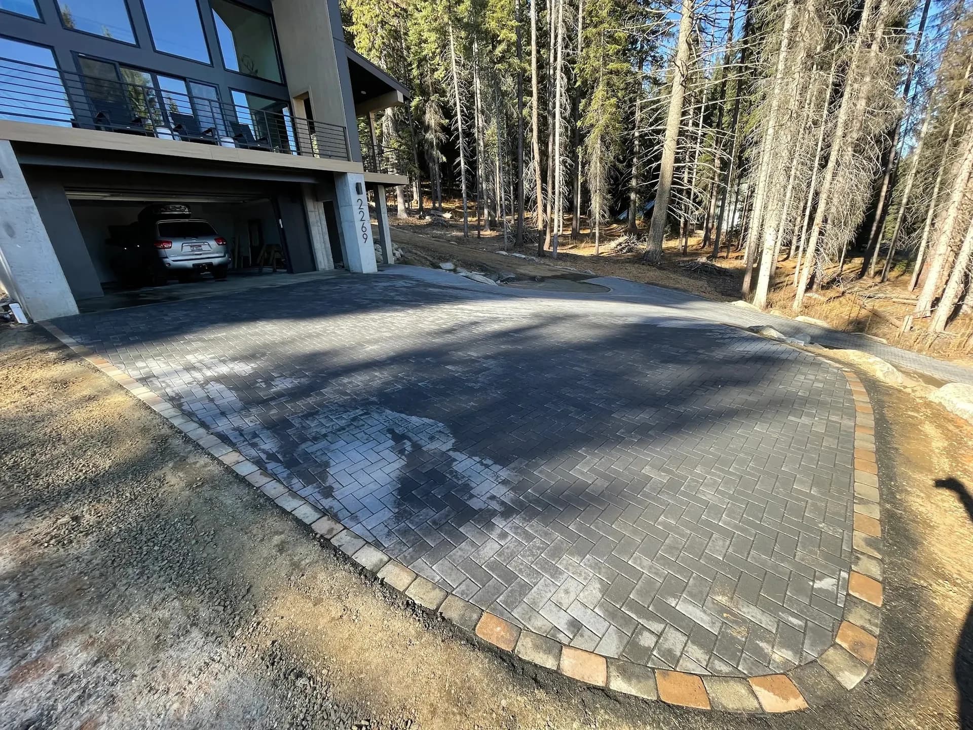 herringbone paver driveway with decorative stone border forest home