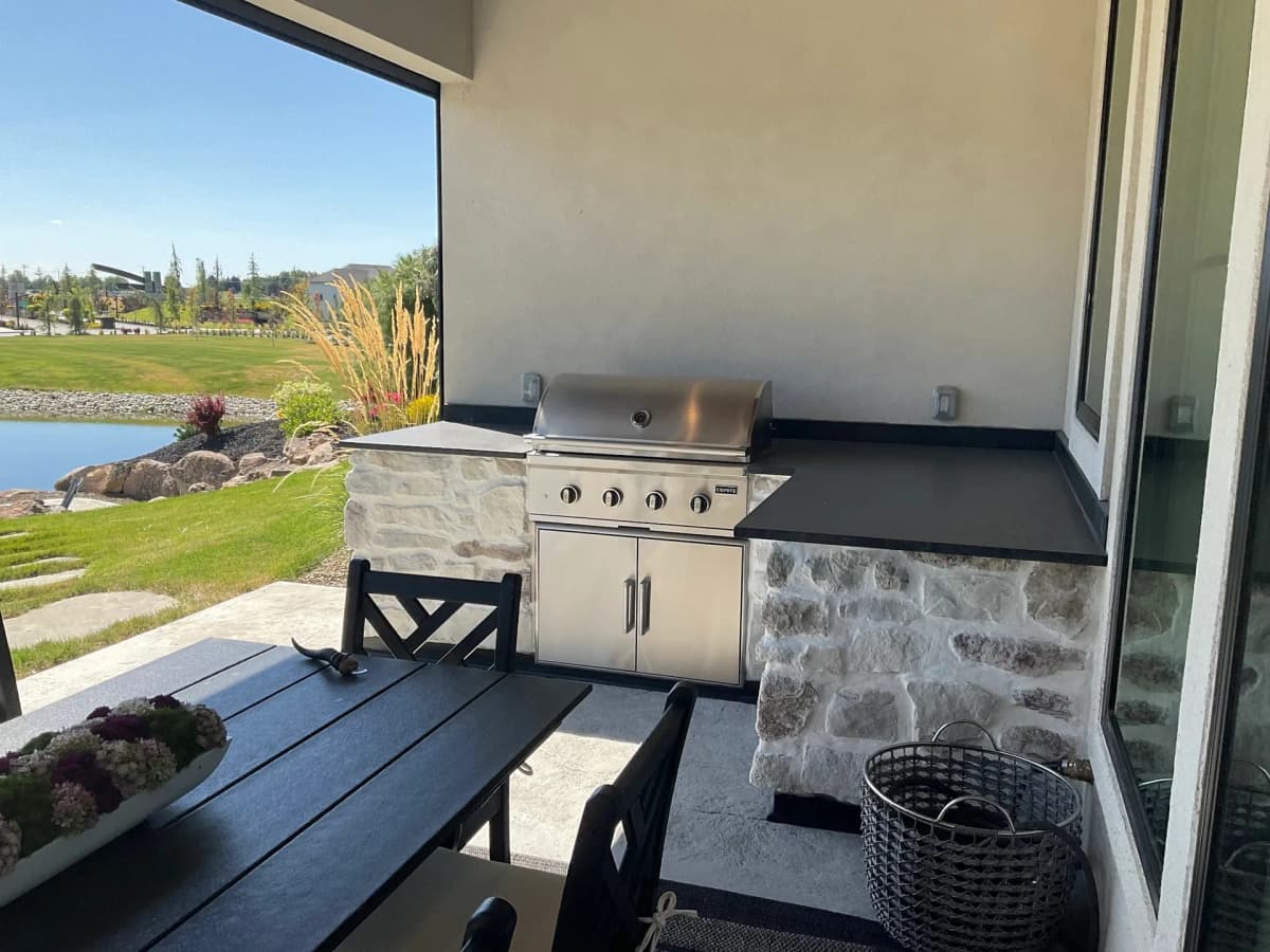outdoor kitchen stone veneer grill island concrete patio lake view